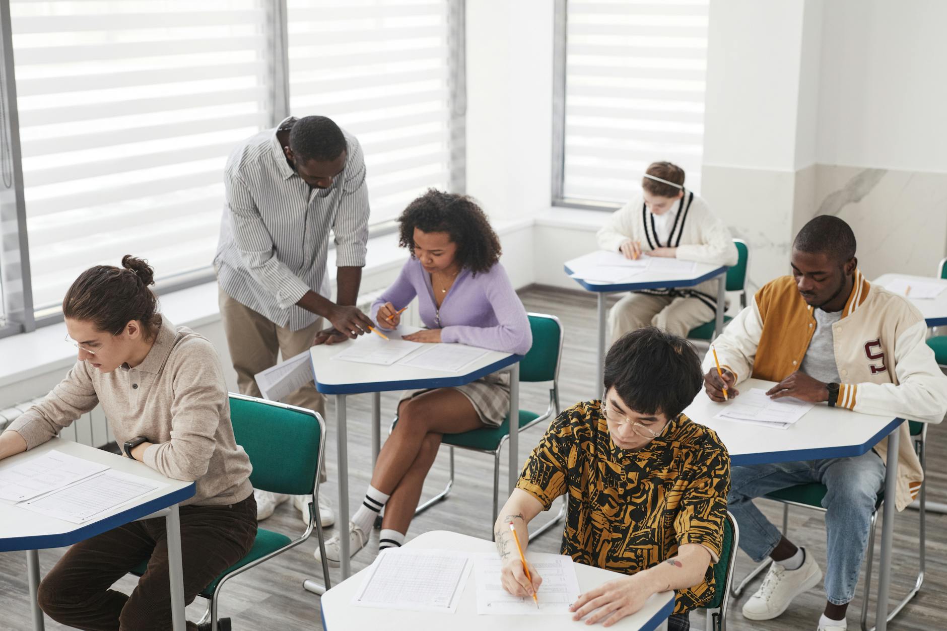 Studenci różnych narodowości piszą egzamin w sali pod okiem wykładowcy