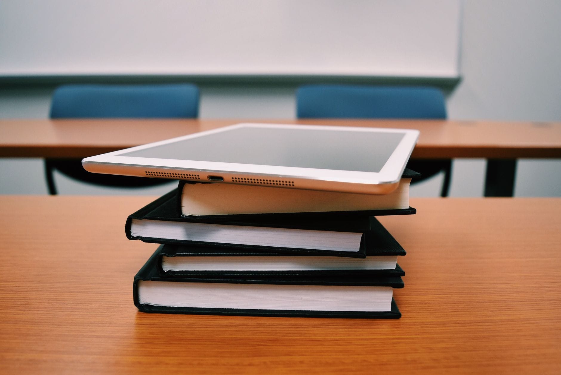 Tablet na stosie książek w pustej sali wykładowej