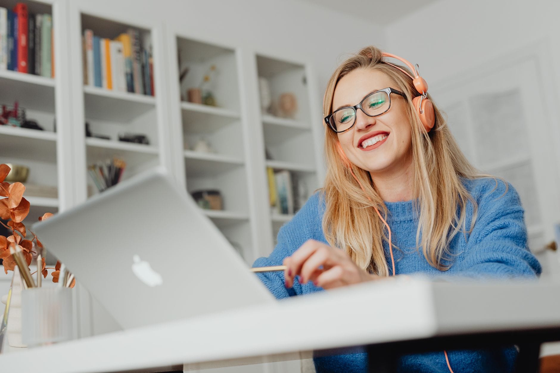 Kobieta w słuchawkach uczy się online na laptopie w domowym biurze